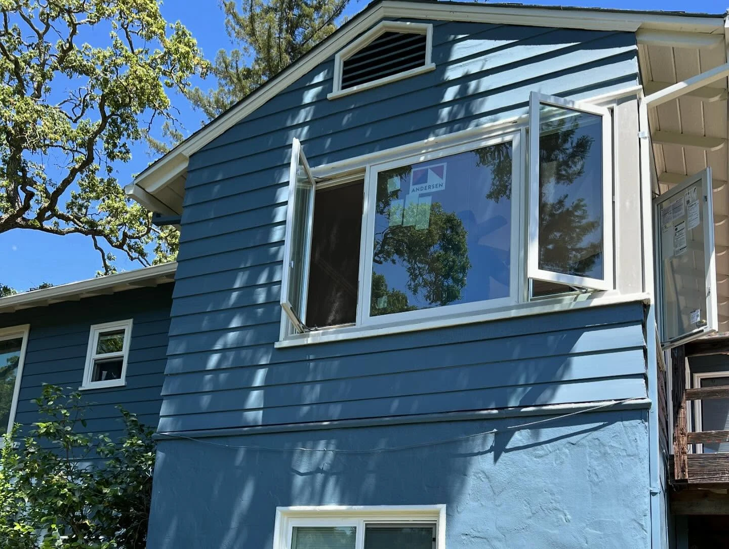 Exterior view of a white Andersen E-Series window configuration on a blue Orinda, CA residence