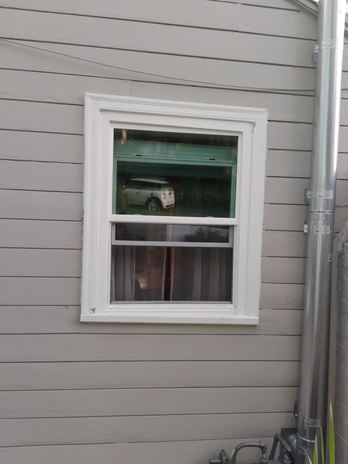 White replacement window with gray exterior siding on a Martinez home