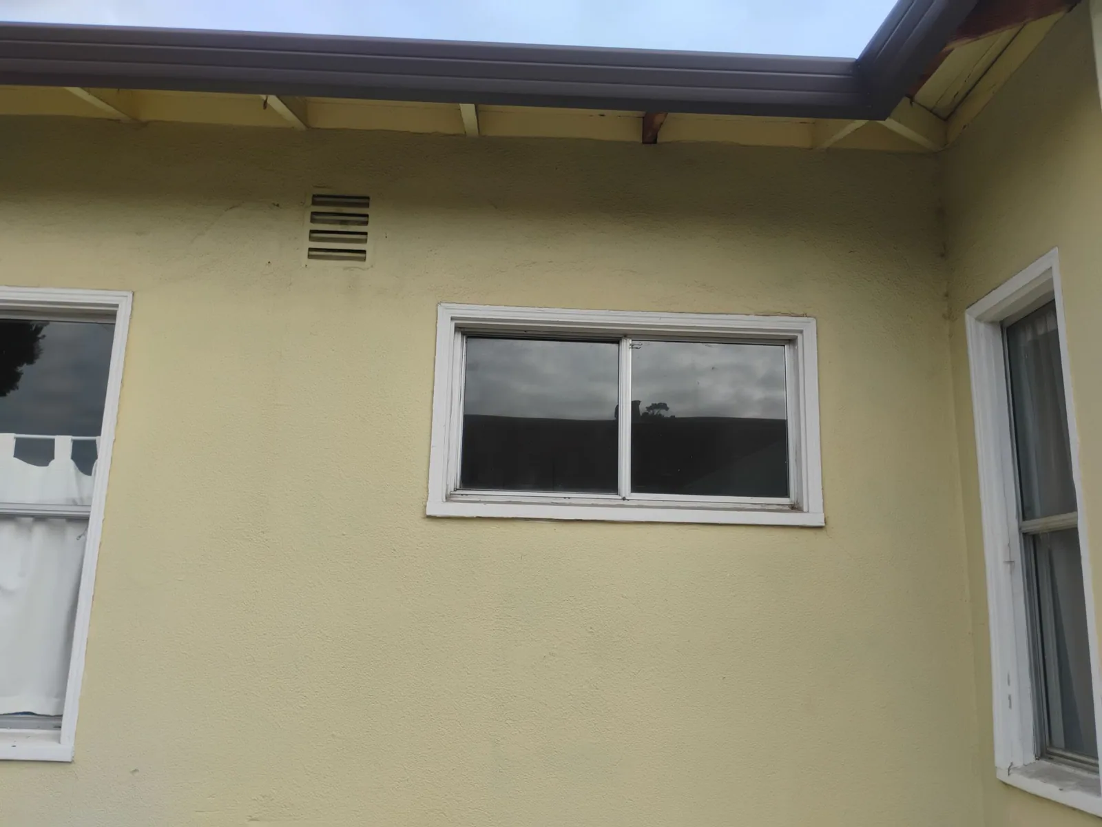 Aging aluminum windows in the stucco exterior before the window replacement
