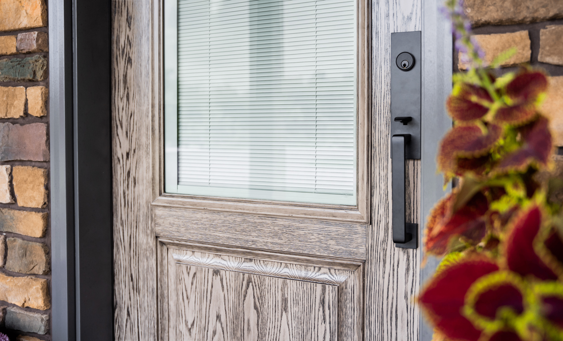 ProVia entry door close-up showing built-in internal blinds sealed between glass panes with a black handleset